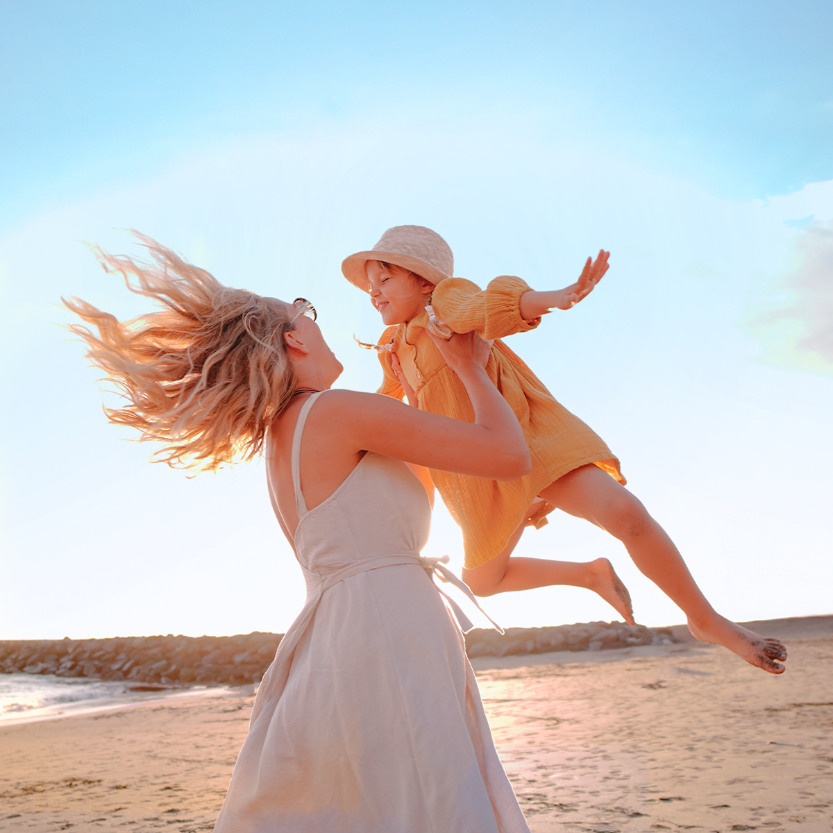 Mother and daughter playing on the beach by the sea.